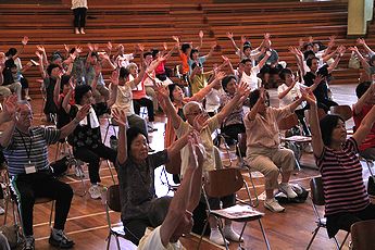 腕を上げる体操をする参加者の写真1