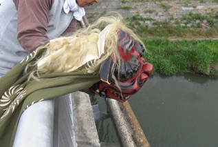 厄除けお獅子様が集めた厄を川に捨てている